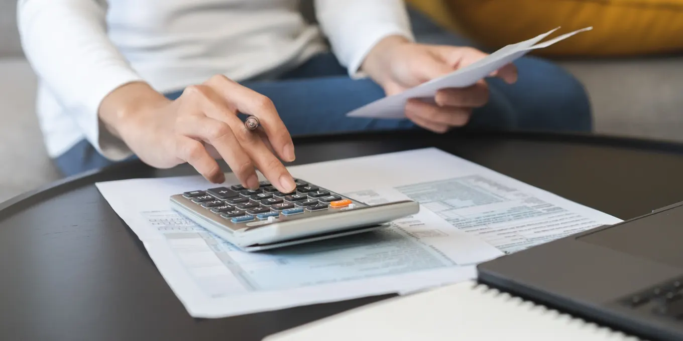 Calculatrice financière, carnet avec calculs manuscrits de mensualités et contrat de crédit à la consommation sur bureau de travail